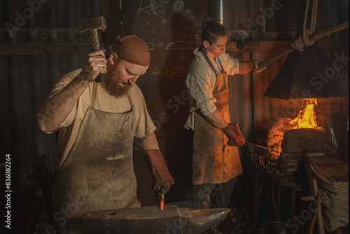 Blacksmith forges a red-hot metal piece on an anvil in a rural forge. Traditional crafts