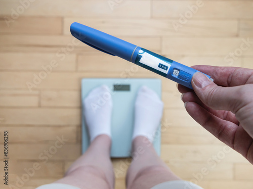  Ozempic Insulin injection pen for diabetics and weight loss. Woman weighs herself and holds Ozempic in her hand.