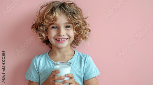 A cheerful child boy holding a glass of milk and flexing his arm muscle in a stretching pose on a vibrant pink background. Perfect for health and fitness themes. AI generative.