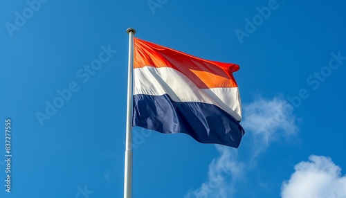Flag of Netherlands waving in the wind. Blue sky background.