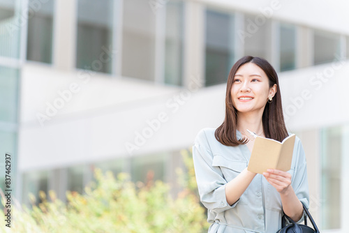 手帳・日記・メモ帳・ノート・スケジュール帳・予定帳に記入する女性・ビジネスウーマン 