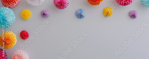 Colorful pom-poms and paper decorations on a white background creating a festive and cheerful atmosphere for celebrations and parties.