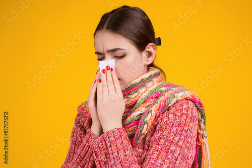 Blow the snot. Woman in sweater and scarf hold napkin blow snot isolated on yellow. Mucus flowing from nose. Girl with snot, runny nose. Suffers from allergy. Nose allergy, flu sneezing nose. Allergy.