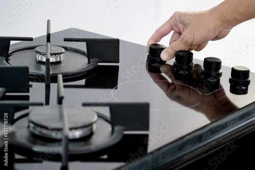 Male hand turning knob on gas hob or gas stove in kitchen showroom. Cooking appliance in the domestic kitchen.