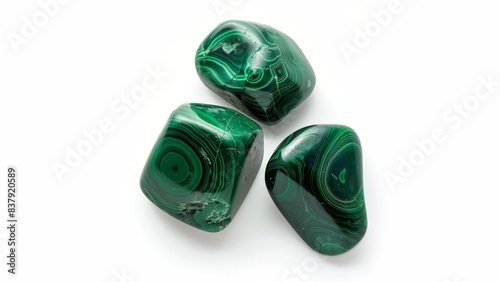 A photo of three tumbled and polished malachite stones with a bit of shine and giving off a slight shadow isolated on a solid white background