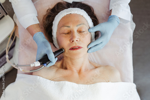 Close-up of mature woman getting facial hydro peeling treatment at cosmetic beauty spa clinic