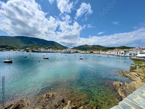 view over the Badia de Cadaqués, to the beautiful white houses of Cadaqués, Port Alguer and the turquoise water of the Mediterranean Sea, mountains of the Pyrenees behind, Girona, Catalonia, Spain