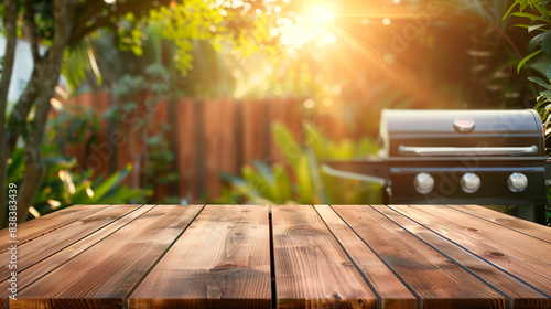 Empty wooden table and blurred view of people having BBQ barbecue with modern grill outdoors