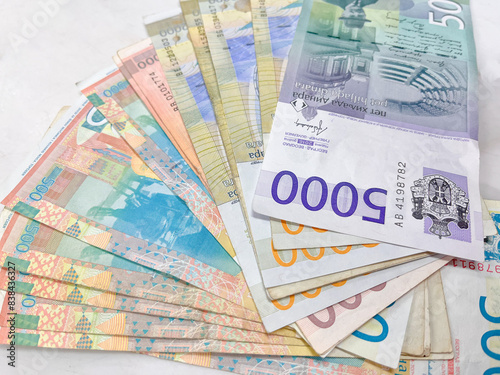 A colorful array of Serbian banknotes, arranged in a fan shape on a textured surface.