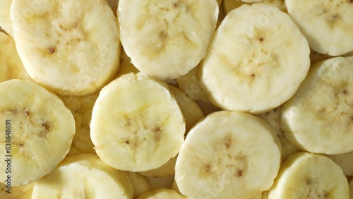 A tantalizing close-up of sliced bananas reveals their creamy white flesh, adorned with delicate brown specks. Each slice exudes a soft, glossy texture, inviting a taste of tropical delight. 