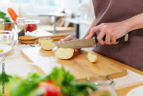 Closeup hands of asian women using knife to cutting slices apple on cutting board to preparing fruits and fresh vegetables of ingredient for cooking breakfast meal while making healthy food lifestyle