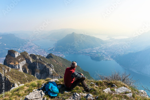 Rear view of hiker sitting on mountaintop, Orobie Alps, Lecco, Italy