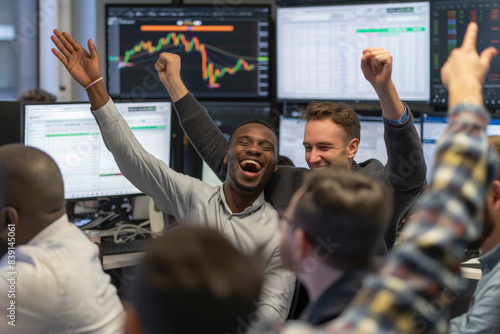 Celebrating success in trading, a group of traders in an office cheer, high-five, and smile after a successful trading day. Computer screens in the background display positive stock market results