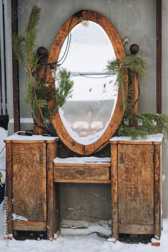 Antique mirror with chest of drawers made of handmade wood with a Christmas tree in the snow. Christmas and New Year's Eve in Lviv, Ukraine.