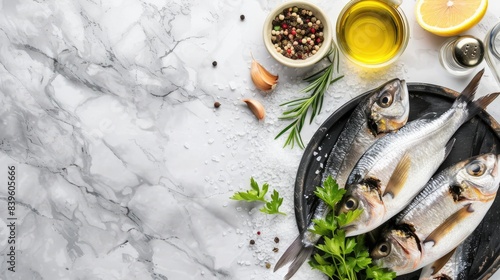 A bowl of fresh sardines on a marble kitchen counter with ingredients for making a simple lemon and salt preparation: olive oil in small white bowls, a spoon