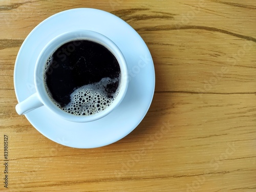 Cup of coffee with foam on the wooden table.