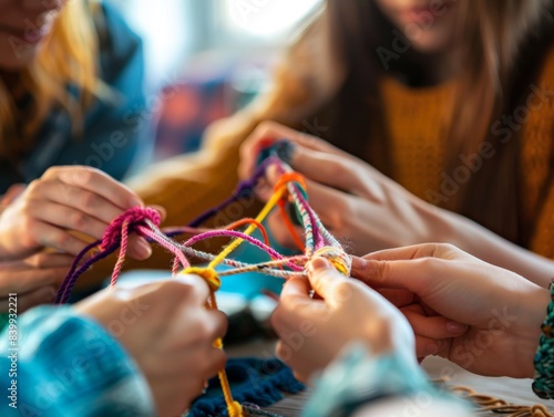 Close-up of friends doing a yarn craft project together. A creative and fun group activity. Hands intertwining colorful threads.