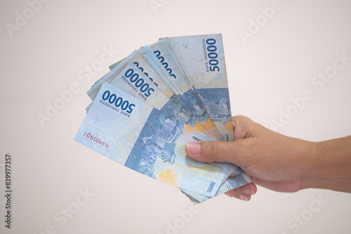 Close up: A woman’s hand holding money; Indonesian rupiah