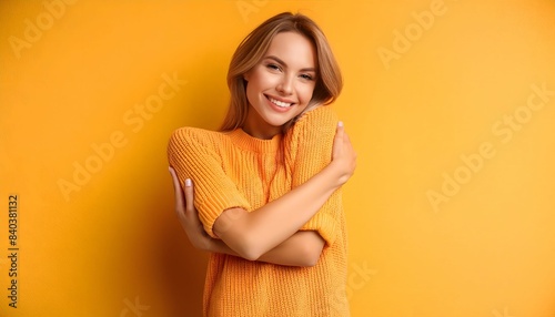 Beautiful young woman on yellow background, happily hugging herself with self-love, concept of self-acceptance - fostering a positive and appreciative relationship with your body