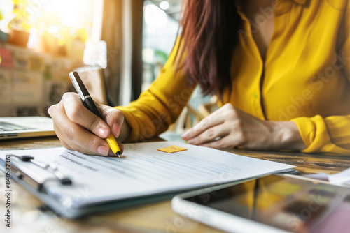 Close-up di ragazza che scrive appunti di studio con una penna gialla su un foglio alla luce del giorno