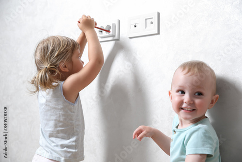 Little children playing with electrical socket indoors. Dangerous situation