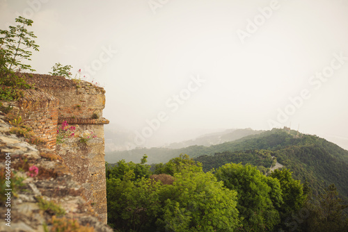 Ancient stone wall. View of foggy valley from medieval Forte Sperone. 