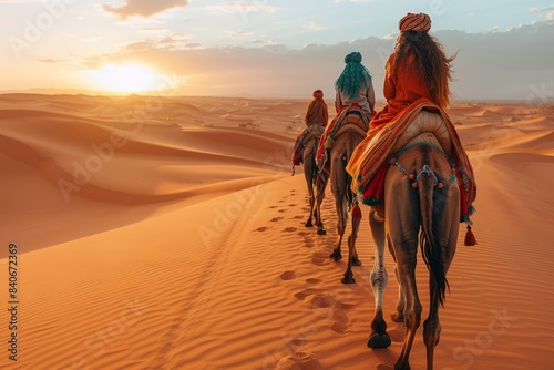 A camel caravan journeys through the Sahara desert at sunset, led by guides.