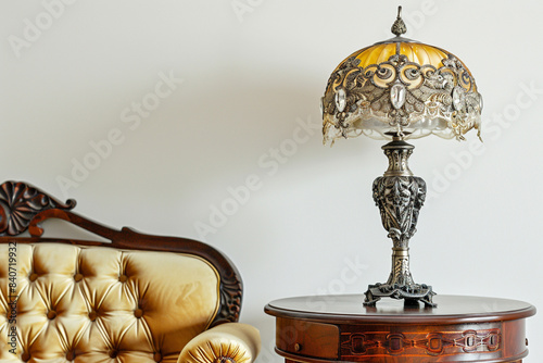 Ornate antique lamp on a mahogany table with a yellow sofa chair, solid white background.