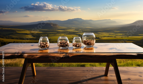 Wooden Table With Snacks and Valley View at Sunset. Four glass bowls filled with snacks sit on a rustic wooden table overlooking a scenic valley at sunset.