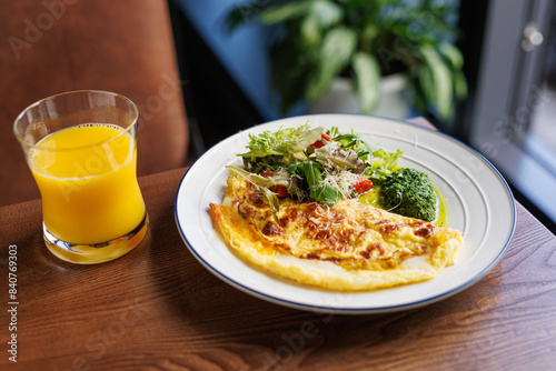 healthy breakfast omelette with herbs grated cheese and a glass of orange juice