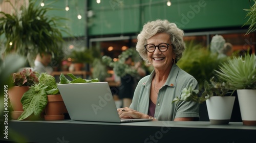 A senior entrepreneur engrossed in work on a laptop, surrounded by lush indoor greenery, embodying the essence of modern remote work