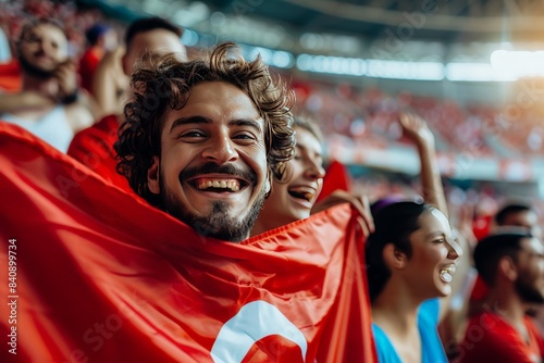 Joyful fan holding a red flag with a crescent and star at a crowded sports stadium
