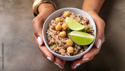 Quinoa salad with chickpeas and lime; healthy vegetarian food concept, diet menu, cookbook, selective focus close up on the dish in hands of a woman
