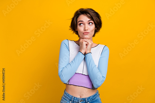 Photo of doubtful unsure lady dressed shirt arms chin looking empty space isolated yellow color background