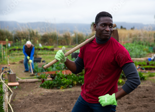 African american man horticulturist with mattock in garden outdoor