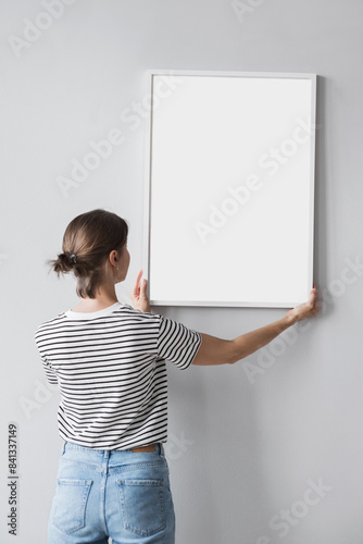 Woman holding blank wooden picture frame mockup on gray wall, Artwork mock-up in minimal interior design, Minimal photographer artist concept