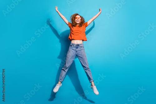 Photo of positive cheerful girl jump up feel carefree isolated blue color background