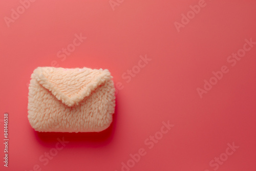 A plushie letter on a red background with copy space. Unique fluffy email icon.