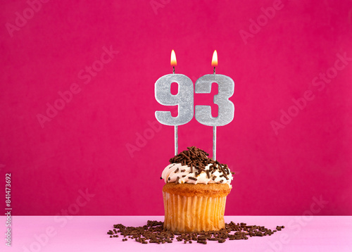 Birthday celebration with candle number 93 - Chocolate cupcake on pink background