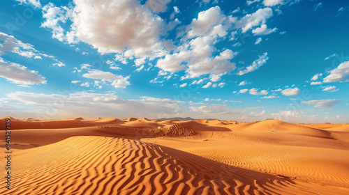 Blue sky and white clouds over golden sand desert dunes