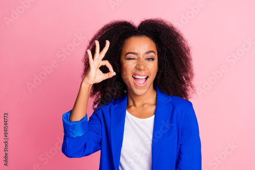 Photo of satisfied pleasaant nice woman with perming coiffure wear blue jacket show okey winking eye isolated on pink color background