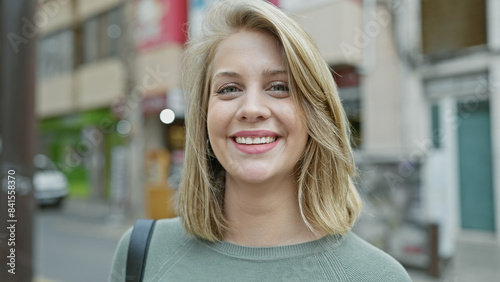 Smiling young adult blonde caucasian woman with short hair on a city street