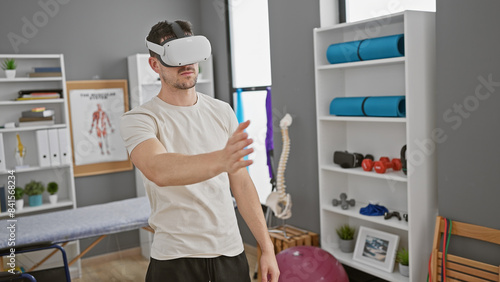 A young hispanic man uses virtual reality in a well-equipped rehabilitation clinic.