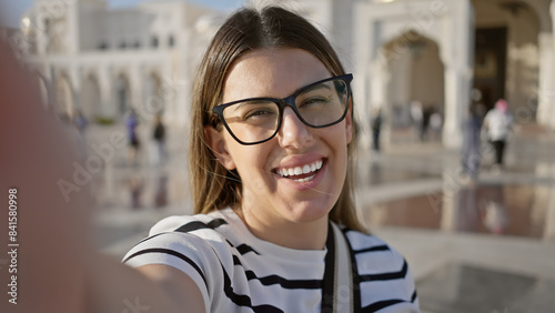 Smiling woman in glasses takes a selfie at qasr al watan in abu dhabi, uae, showcasing tourism and architecture.