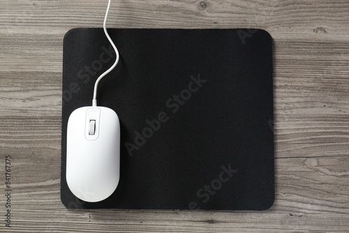 Wired mouse and mousepad on wooden table, top view