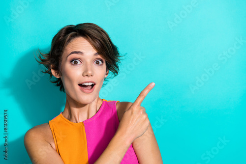 Photo of excited cheerful woman wear pink orange top showing finger empty space isolated teal color background
