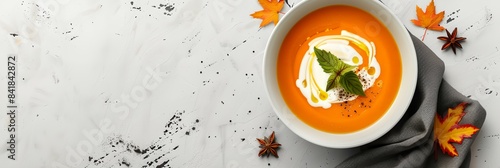 a bowl of carrot soup with cream and leaves on a table