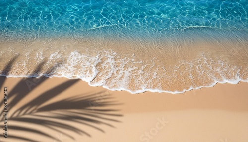 abstract sand beach with palm leaf shadow and blue water wave from above summer vacation outdoors in tropical paradise nature background with space