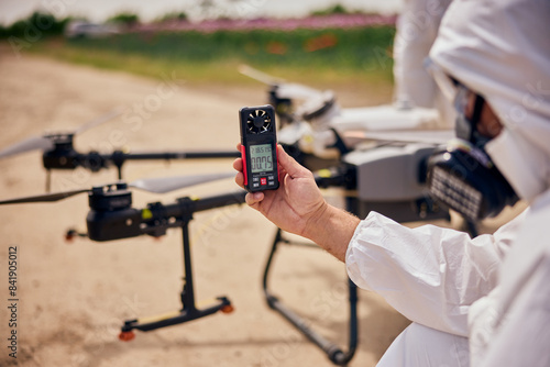 A male operator holding and using a hand-held anemometer tested the air flowing before starting the agro drone.