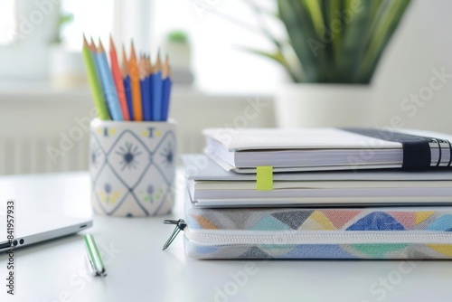 A white table with a stack of hardcover textbooks a sleek pencil case and a single geometric set for a minimalist academic look